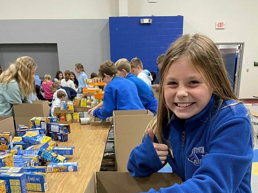SCA sixth grade student Aubrey Yates helped pack up some of the nearly 10,000 items donated by elementary families to bless Kansas City families with a Thanksgiving meal this season.