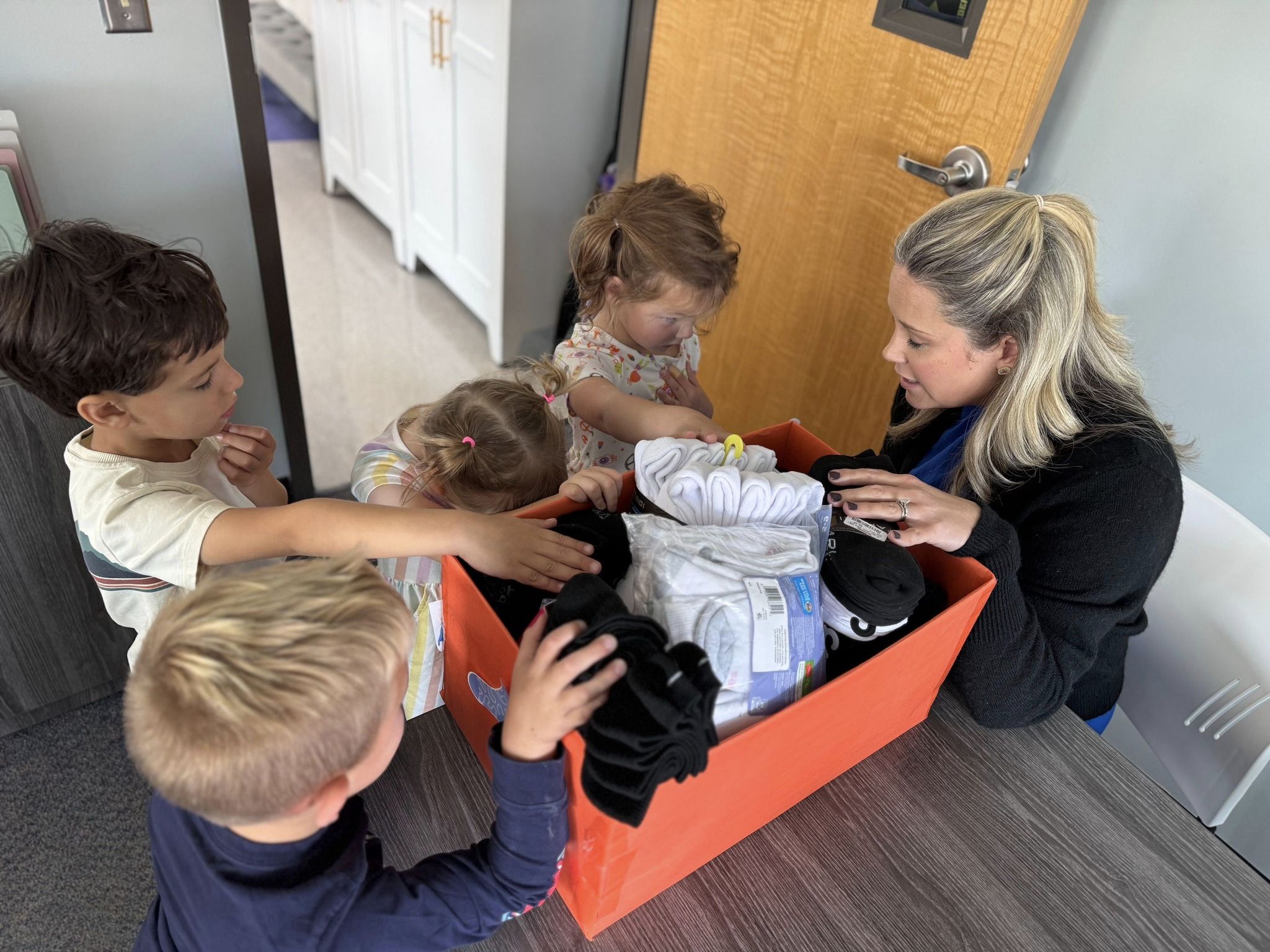 SCA Early Education students and Early Education Director Jessica Fisher pray over the men, women, and children who will receive the 532 pairs of new socks donated by SCA Early Educations students and families.