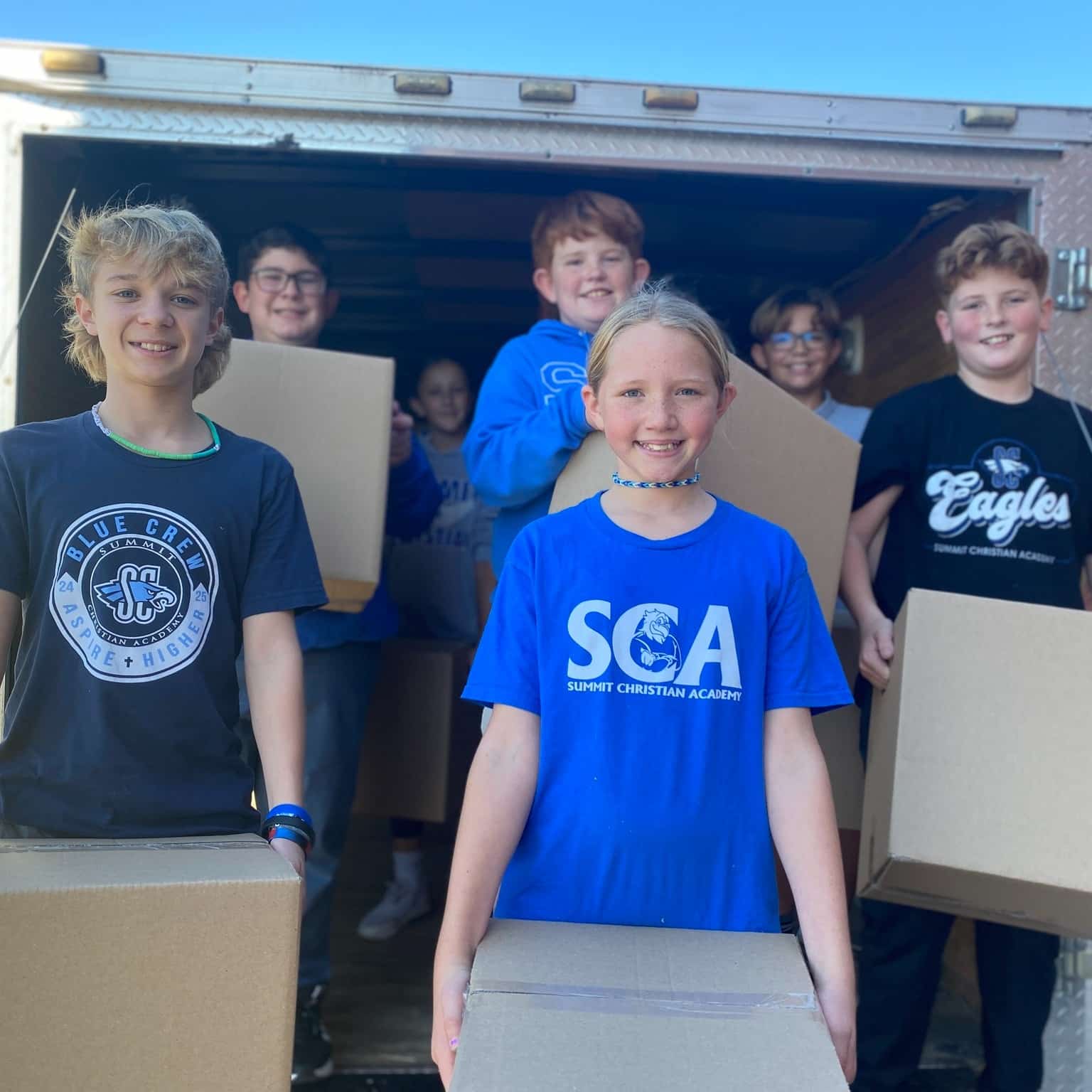 At the 16th annual SCA Elementary Food Drive, sixth grade students (l-r) Nolan Richards, Daniel Elizondo, Cecilia Kirkpatrick, Brayden Lightle, Rylann Pfeifer, Isaiah Hale, and Gabe Olla help pack trucks with some of the nearly 5,000 units of food donated by SCA students in time for local churches to distribute them for Thanksgiving.